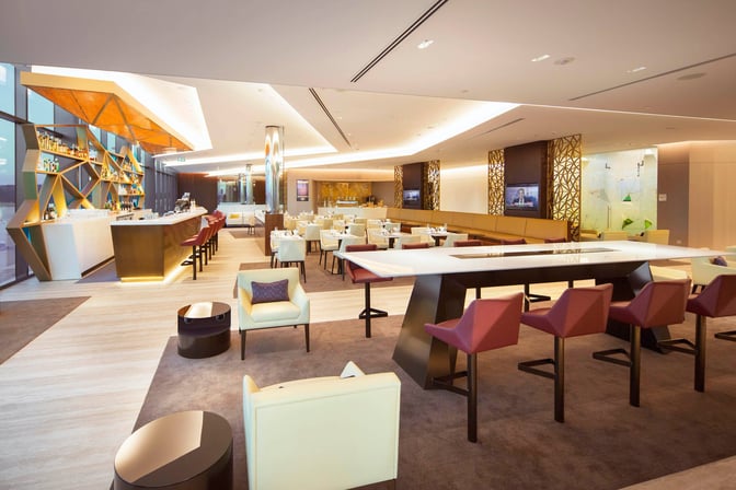 The House by Aspire lounge at Melbourne Airport features a bar with counter seating and a spacious dining area with tables.