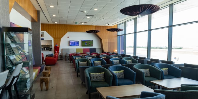 The seating area in Adinkra Lounge at Kotoka International Airport features comfortable chairs, tables, and large windows with tarmac views.