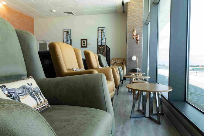 Comfortable seating at Adinkra Lounge, Kotoka International Airport, offers views of the runway through large windows, with nearby tables.