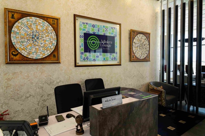 The reception area of Adinkra Lounge at Kotoka International Airport features a check-in desk with seating and decorative wall art.