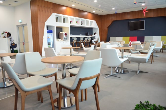 The Akwaaba Lounge at Kotoka International Airport features a seating area with tables and chairs, a beverage station, and a reception desk.