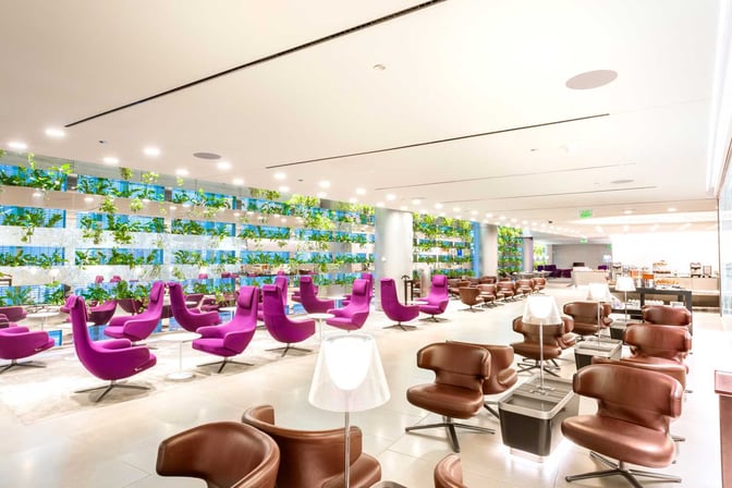 The Al Maha Lounge at Doha Hamad International Airport features spacious seating with individual chairs and a self-serve refreshment area.