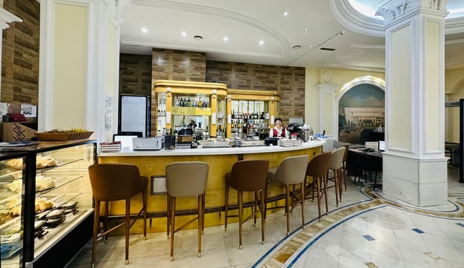 The Primeclass Lounge at Almaty International Airport features a bar with seating and a display case offering snacks.