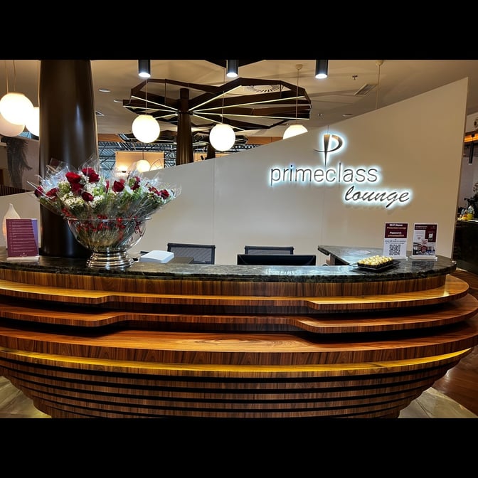 The reception desk at Primeclass Lounge in Ivato International Airport features a welcoming counter with informational brochures and floral arrangements.
