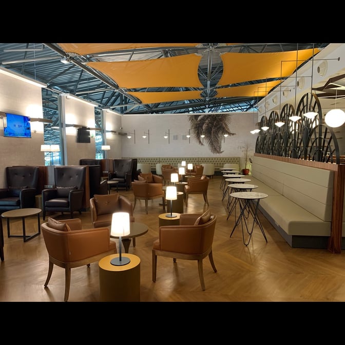 The Primeclass Lounge at Ivato International Airport features a seating area with armchairs, tables, and ambient lighting for travelers.