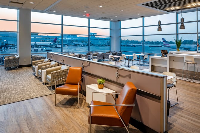 The Aspire Lounge at San Diego International Airport features diverse seating options with views of the runway through large windows.