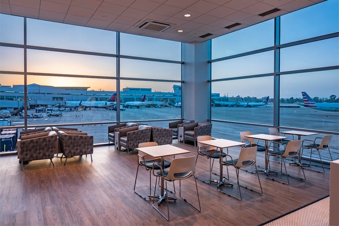 The Aspire Lounge at San Diego International Airport features seating with views of the runway through large windows.