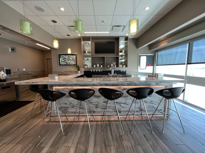 The Aspire Lounge at Ontario International Airport features a bar with counter seating, offering a selection of wines and spirits.