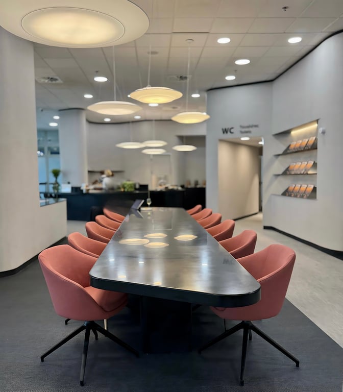 The Goldair Handling x AIA Lounge at Athens International Airport features a long communal table with seating and overhead lighting.