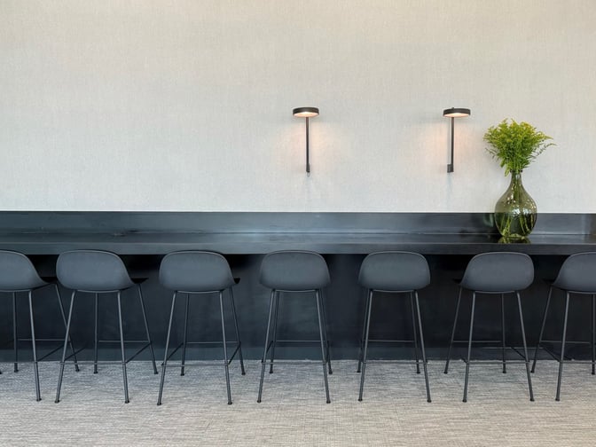 The seating area in the Goldair Handling x AIA Lounge features a long counter with bar stools and wall-mounted lighting.