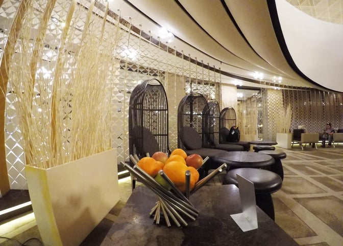 The seating area in Absheron Lounge features round tables and unique chair designs, providing a comfortable space for travelers.