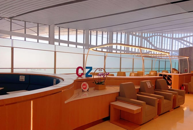 The China Southern First/Business Class Lounge at Beijing Daxing International Airport features seating areas with individual tables and a curved counter.