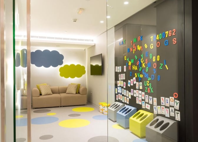 The children's play area in Ahlein Premium Lounge at Beirut Airport features a sofa, wall-mounted TV, and magnetic alphabet board.