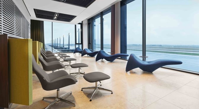 Seating area in Lounge Tempelhof at Berlin Brandenburg Airport features ergonomic chairs and loungers with expansive views of the runway.
