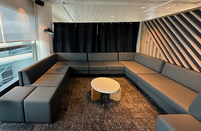 The seating area in the Plaza Premium Lounge at Brisbane Airport features a large L-shaped sofa and a central round table.