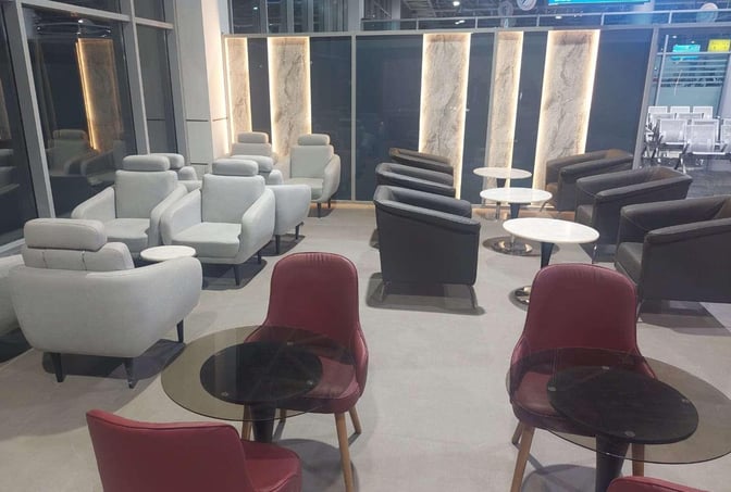 The seating area in the CAC Lounge at Cairo International Airport features various armchairs and small tables for passenger comfort.