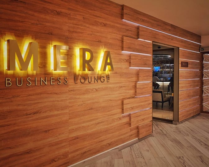 The entrance to the MERA Business Lounge at Cancun International Airport's Terminal 4 features a wooden wall with illuminated signage.