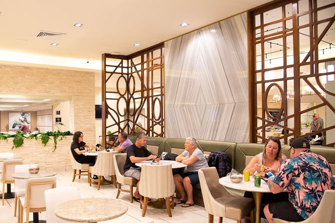 Seating area at MERA Business Lounge Terminal 4 International, Cancun Airport, features tables and chairs for dining and relaxation.