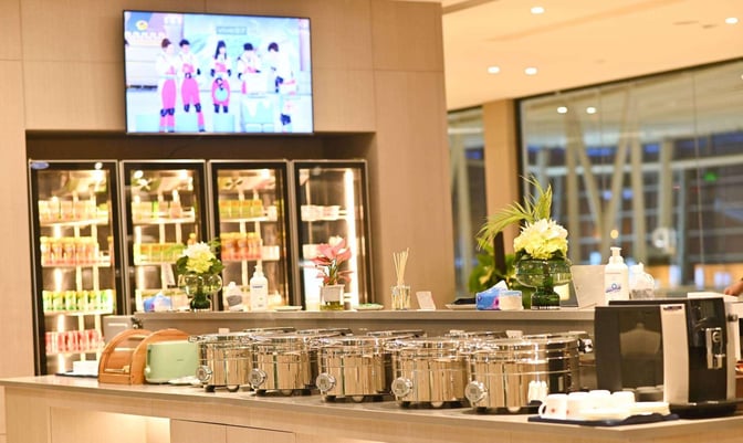 The China Southern First/Business Class Lounge at Changsha Airport features a self-serve food area with hot dishes and refrigerated beverages.