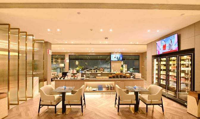 The China Southern First/Business Class Lounge at Changsha Airport features a self-serve food and beverage area with seating and refrigerated displays.