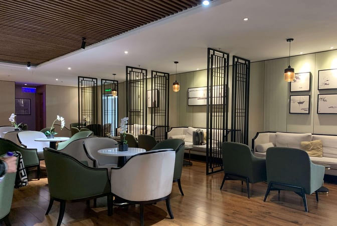 The seating area in Joyflight No.7 First Class Lounge at Changsha Airport features tables with chairs and semi-private couches.