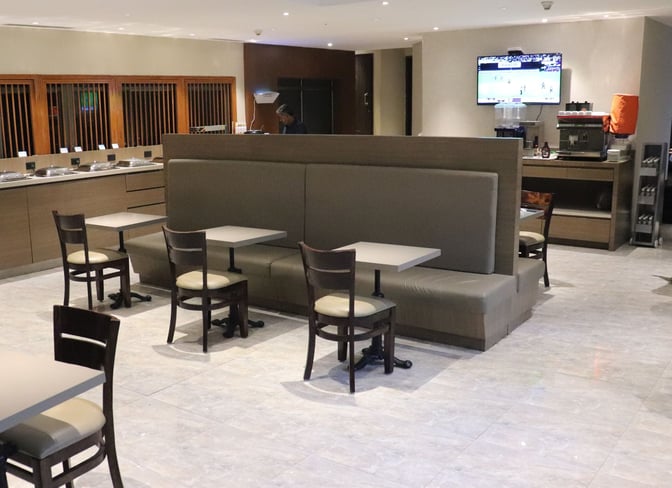 Booth seating in Travel Club Lounge A at Chennai International Airport offers dining tables.