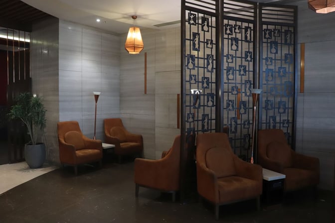 Seating area in Travel Club Lounge B at Chennai International Airport features comfortable chairs and decorative partitions for privacy.