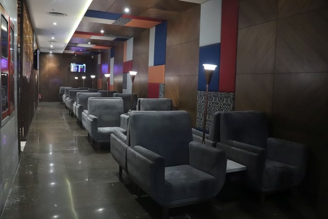 The seating area in Travel Club Lounge B at Chennai International Airport features rows of armchairs with individual lamps.