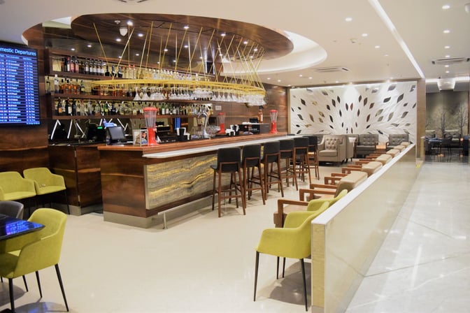 The Travel Club Lounge at Chhatrapati Shivaji International Airport features a bar with seating and a variety of displayed beverages.