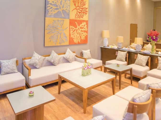 Seating area in The Coral Executive Lounge at Chiang Mai International Airport features cushioned chairs and tables for passenger relaxation.