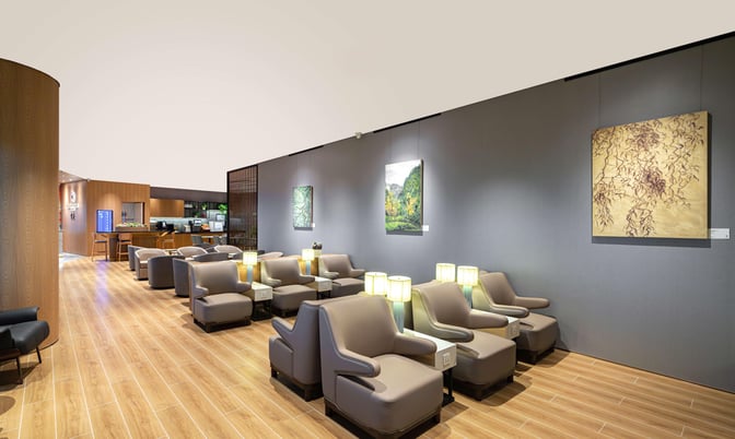 The seating area in Plaza Premium Lounge at Chongqing Airport features comfortable chairs with individual lamps and nearby charging outlets.