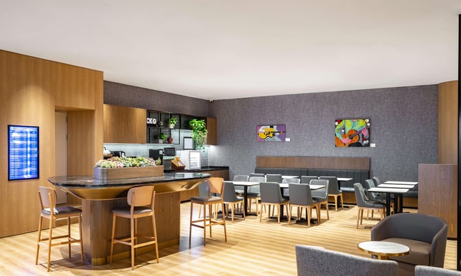 The Plaza Premium Lounge at Chongqing Jiangbei International Airport features a seating area with tables, chairs, and a central bar counter.