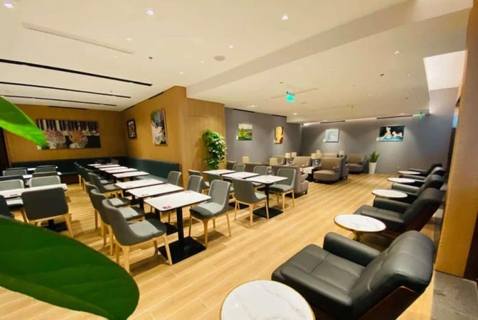 The Plaza Premium Lounge at Chongqing Jiangbei International Airport features a seating area with tables and chairs for dining and relaxation.