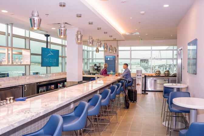 The Club CLE at Cleveland Hopkins International Airport features a bar area with counter seating and views of the tarmac.