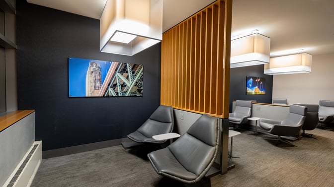 The seating area in The Club CLE at Cleveland Hopkins International Airport features lounge chairs and small tables for travelers.