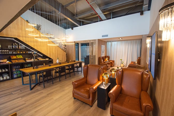 The W Lounge Calafate features a seating area with leather armchairs and a self-serve food station offering snacks and beverages.