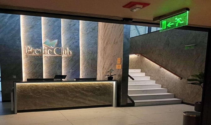 The entrance to the Pacific Club Lounge at Comodoro Arturo Merino Benítez International Airport features a reception desk and staircase.