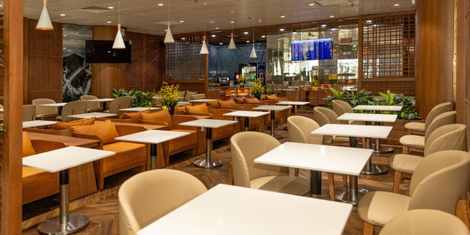 The SH Premium Lounge at Da Nang International Airport features table seating and a refreshment area with a flight information screen.