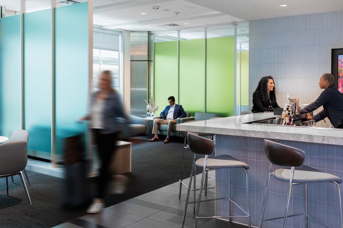 The Club DFW lounge features a bar area with counter seating and a separate seating area for relaxation and socializing.