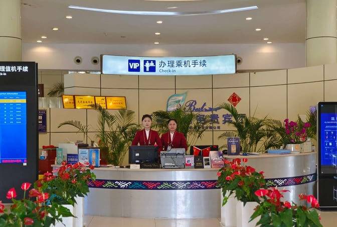 The VIP check-in area at Dehong Mangshi Airport features a staffed reception desk with digital flight information displays.