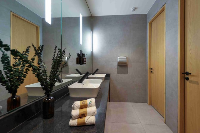 The restroom at Sleepover North Node in Doha Hamad International Airport features dual sinks, mirrors, and complimentary toiletries.