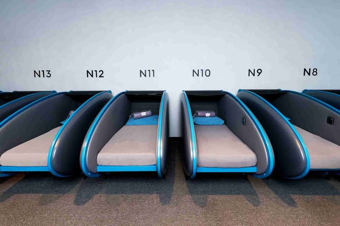 The Sleepover North Node at Doha Hamad International Airport features individual sleeping pods with numbered designations for passenger rest.