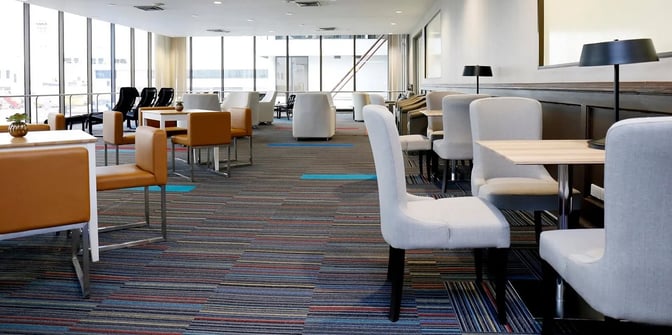 The seating area in Miracle Lounge No. 1 at Don Mueang International Airport features tables with chairs and armchairs, offering airport views.