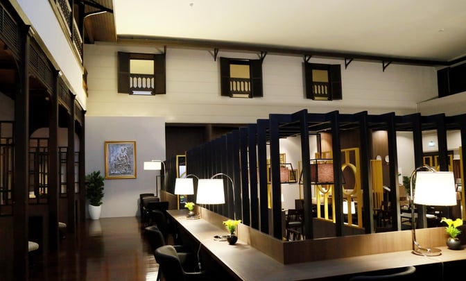 The Miracle Lounge at Don Mueang International Airport features a seating area with workstations, lamps, and semi-private partitions for travelers.