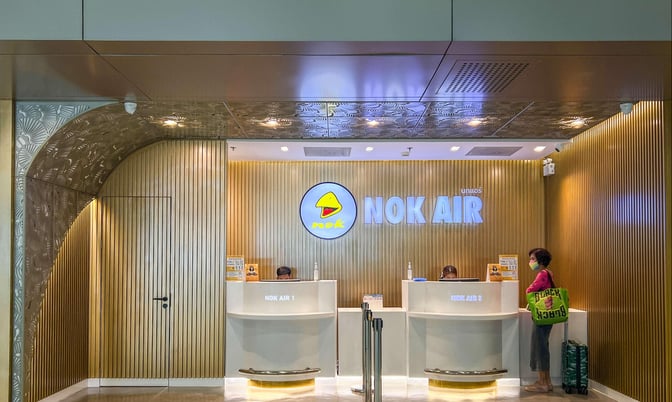 The Nok Air Lounge entrance at Don Mueang International Airport features reception desks with staff ready to assist passengers.