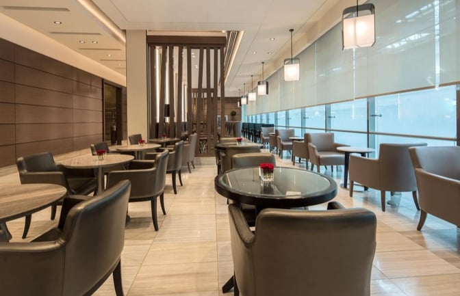 The Ahlan Business Class Lounge at Dubai International Airport Concourse D features a seating area with tables and chairs, offering airport views.