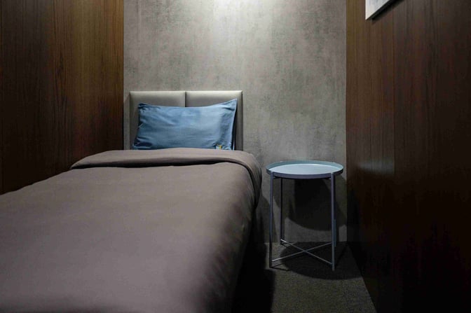 A private sleeping pod at Dubai International Airport's Sleepover Lounge offers a bed and side table for passenger rest.