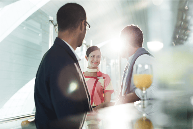 A staff member at marhaba Lounge, Dubai International Airport, Terminal 2, assists guests near a counter with a glass of orange juice.