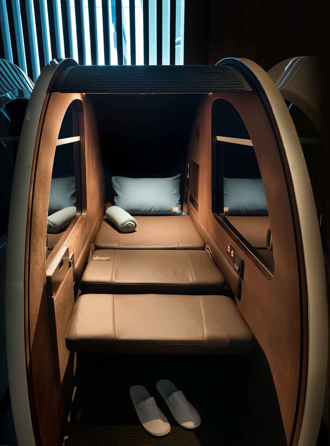 The sleep pod at Dubai International Airport's Concourse A lounge offers a private resting space with a pillow and slippers.