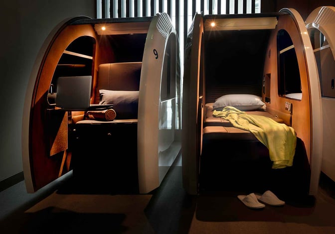 Sleeping pods at Dubai International Airport's Sleepover Lounge in Concourse A offer private resting spaces with bedding and personal lighting.